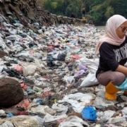 Mensen bij een rivier vol met plastic afval